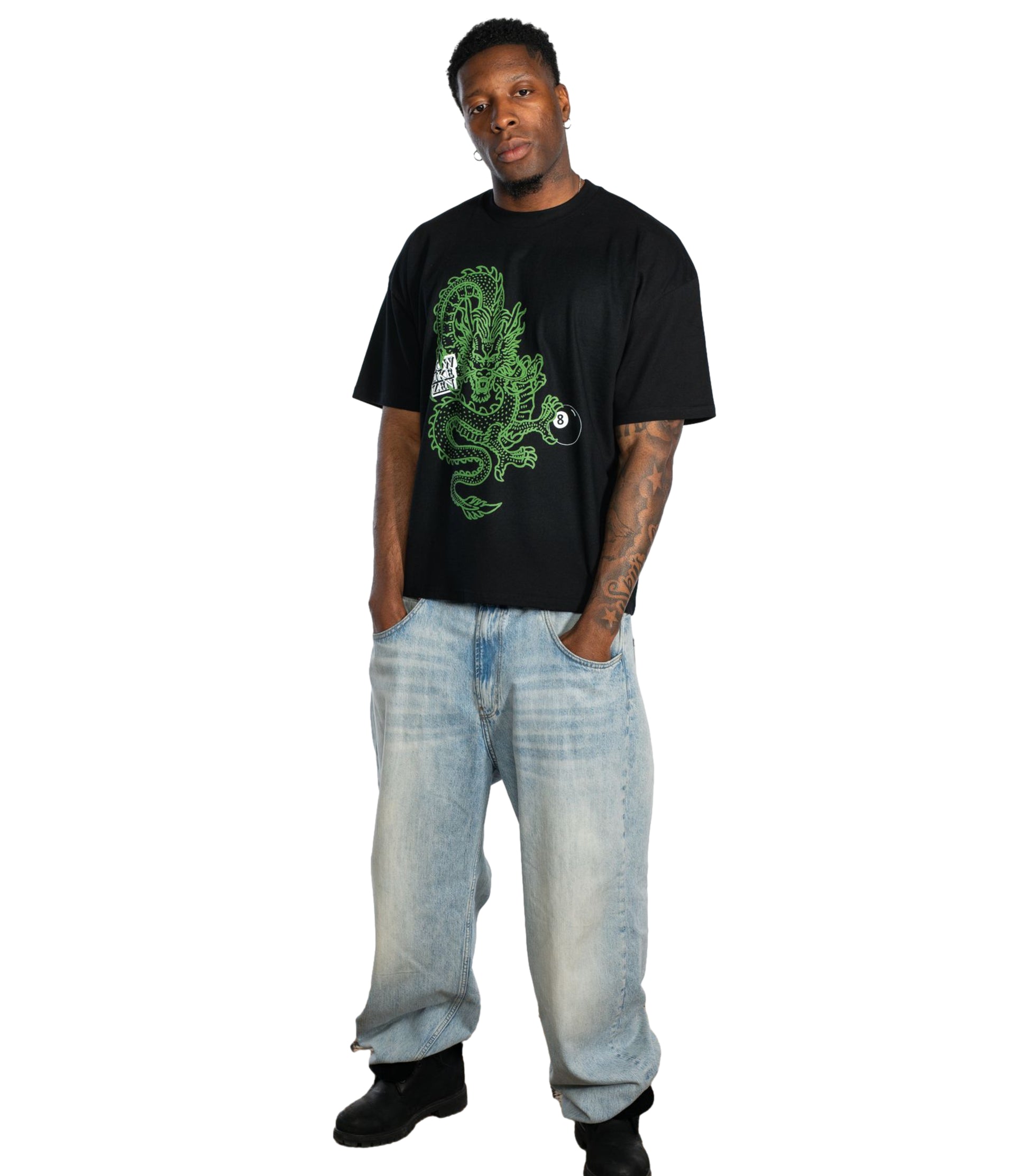 Male model wearing Flow Like Zen Dragon’s Grip black oversized t-shirt with green dragon and 8-ball graphic, styled with baggy denim jeans and black boots; UK streetwear brand rooted in British urban fashion culture.