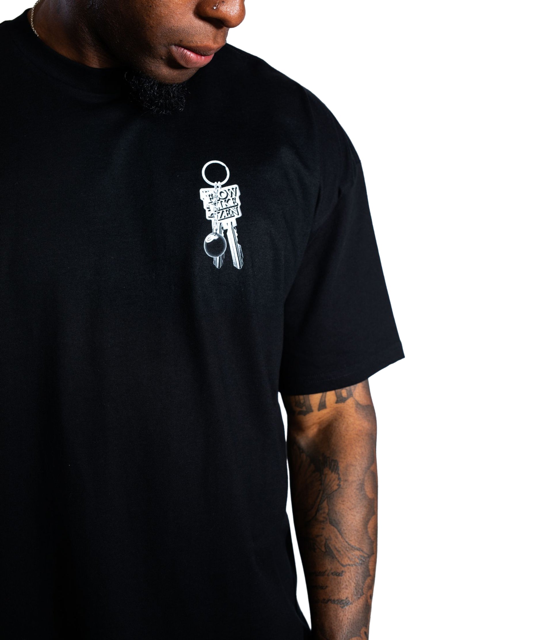 Close-up of black Flow Like Zen t-shirt with small chest graphic of silver keychain and 8-ball – oversized UK streetwear tee for men.