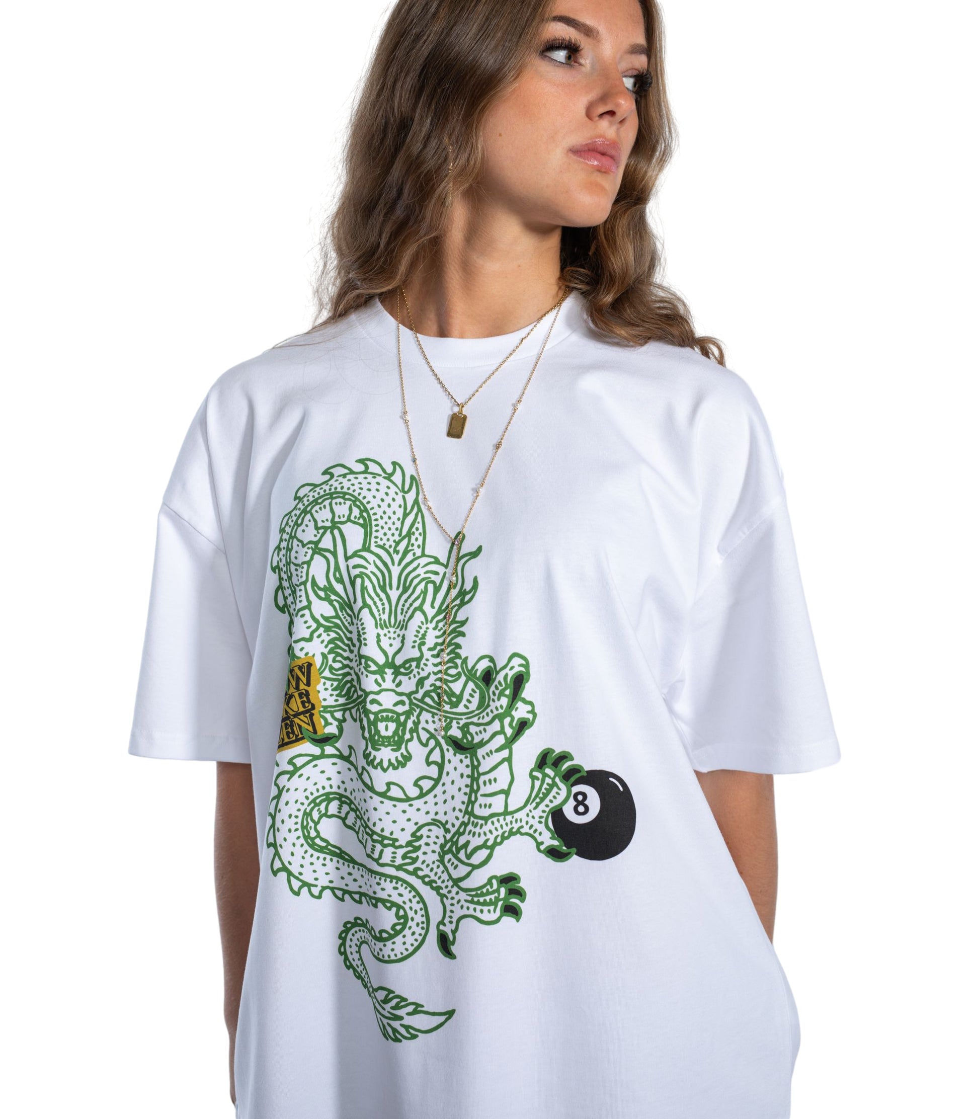 Female model wearing Flow Like Zen Dragon’s Grip white oversized graphic t-shirt featuring green dragon and 8-ball artwork; premium British streetwear with unisex urban style, made in the UK.