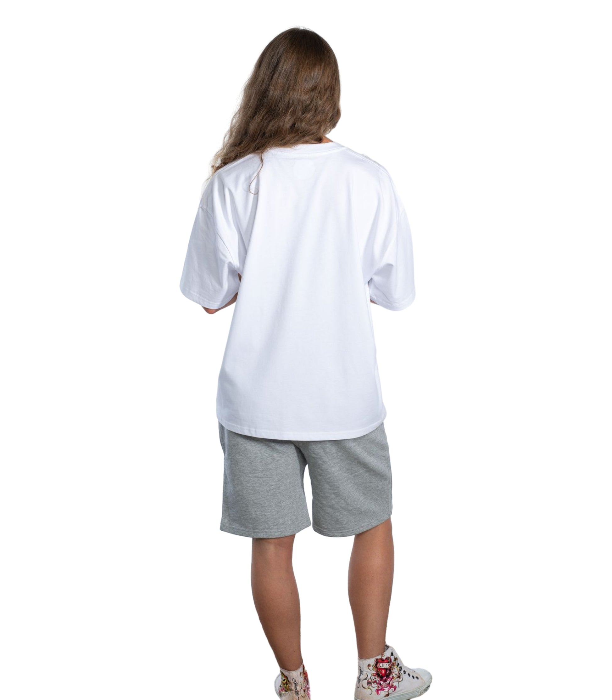 Back view of model wearing oversized white Flow Like Zen t-shirt and grey shorts, showcasing minimalist British streetwear style; unisex urban fashion designed in the UK.