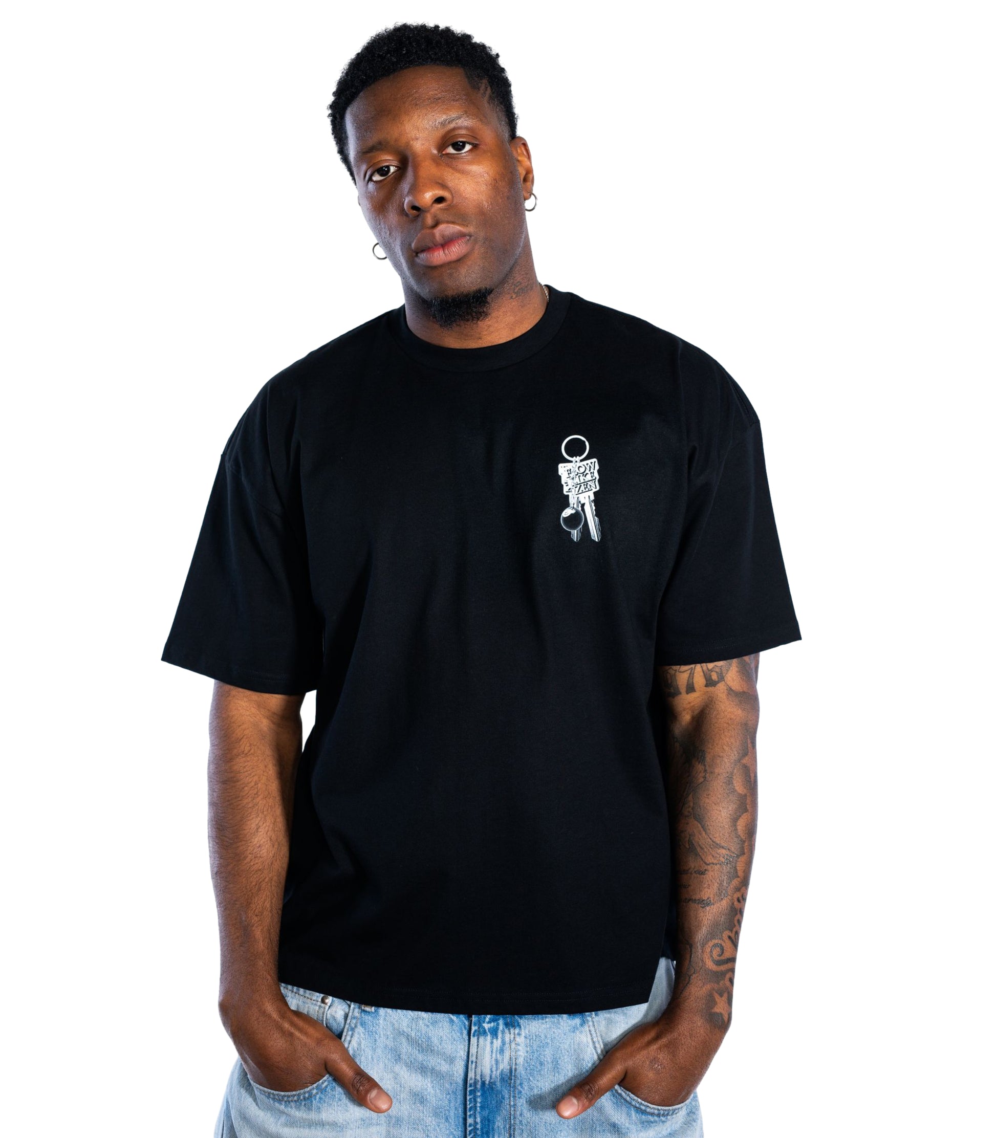 Male model wearing oversized black Flow Like Zen t-shirt with small silver keychain chest print – UK independent streetwear brand.