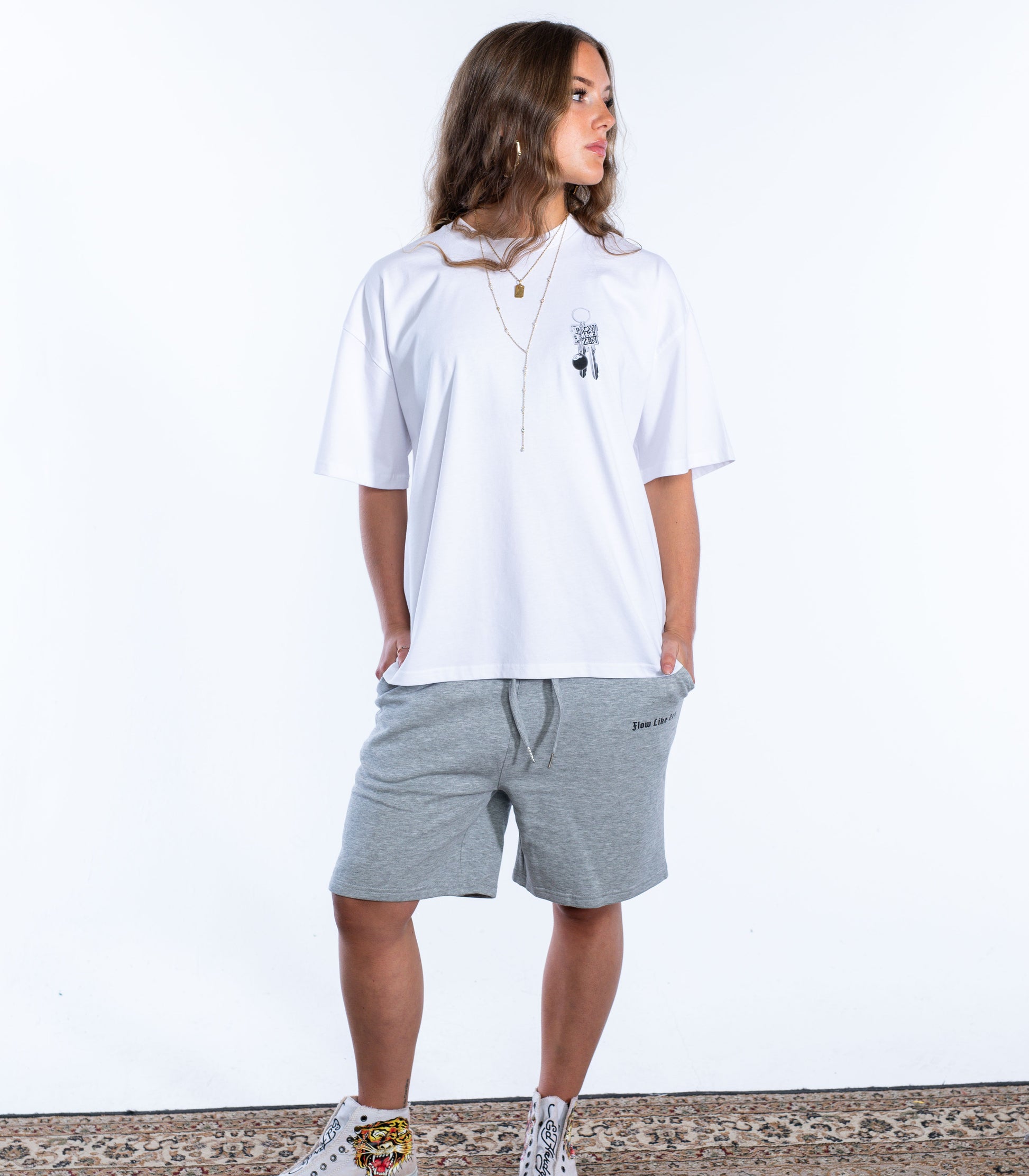 Front view of woman wearing oversized white Flow Like Zen t-shirt with small chest print featuring metallic keychain and 8-ball graphic – British streetwear brand.