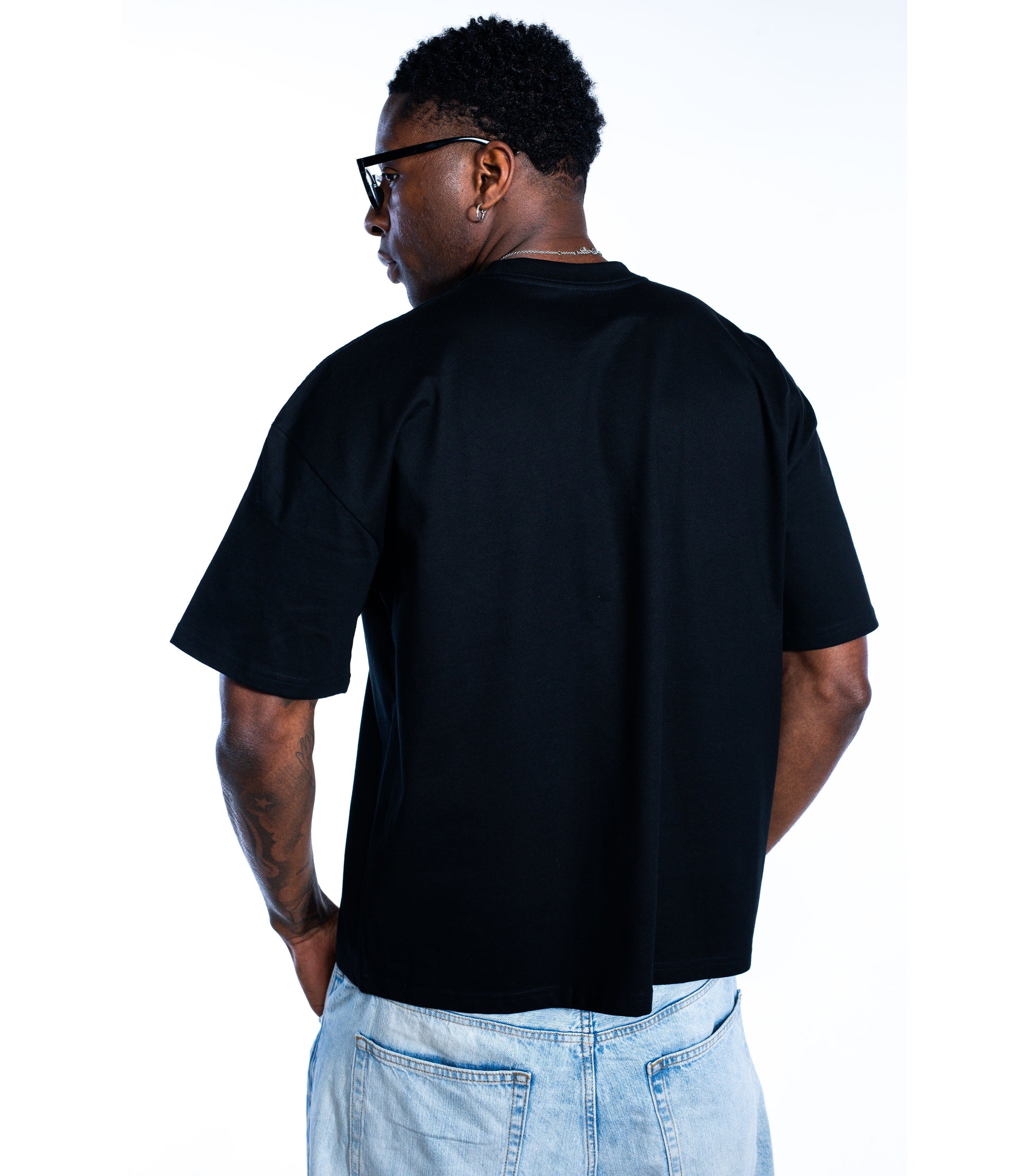 Back view of male model wearing Flow Like Zen black t-shirt – premium minimalist British streetwear design